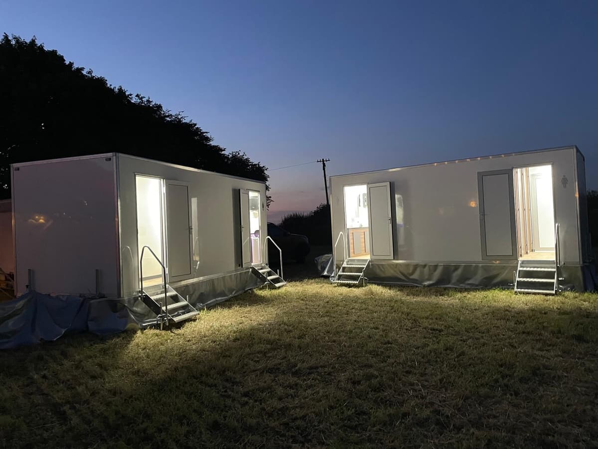 Two luxury trailers lit up at dusk event